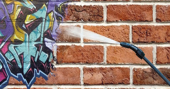 Professionals are removing Graffiti from a wall
